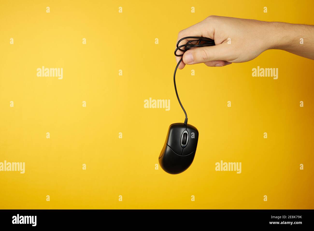 The black computer mouse at hand on a yellow background with copy space. hardware maintenance service concept Stock Photo