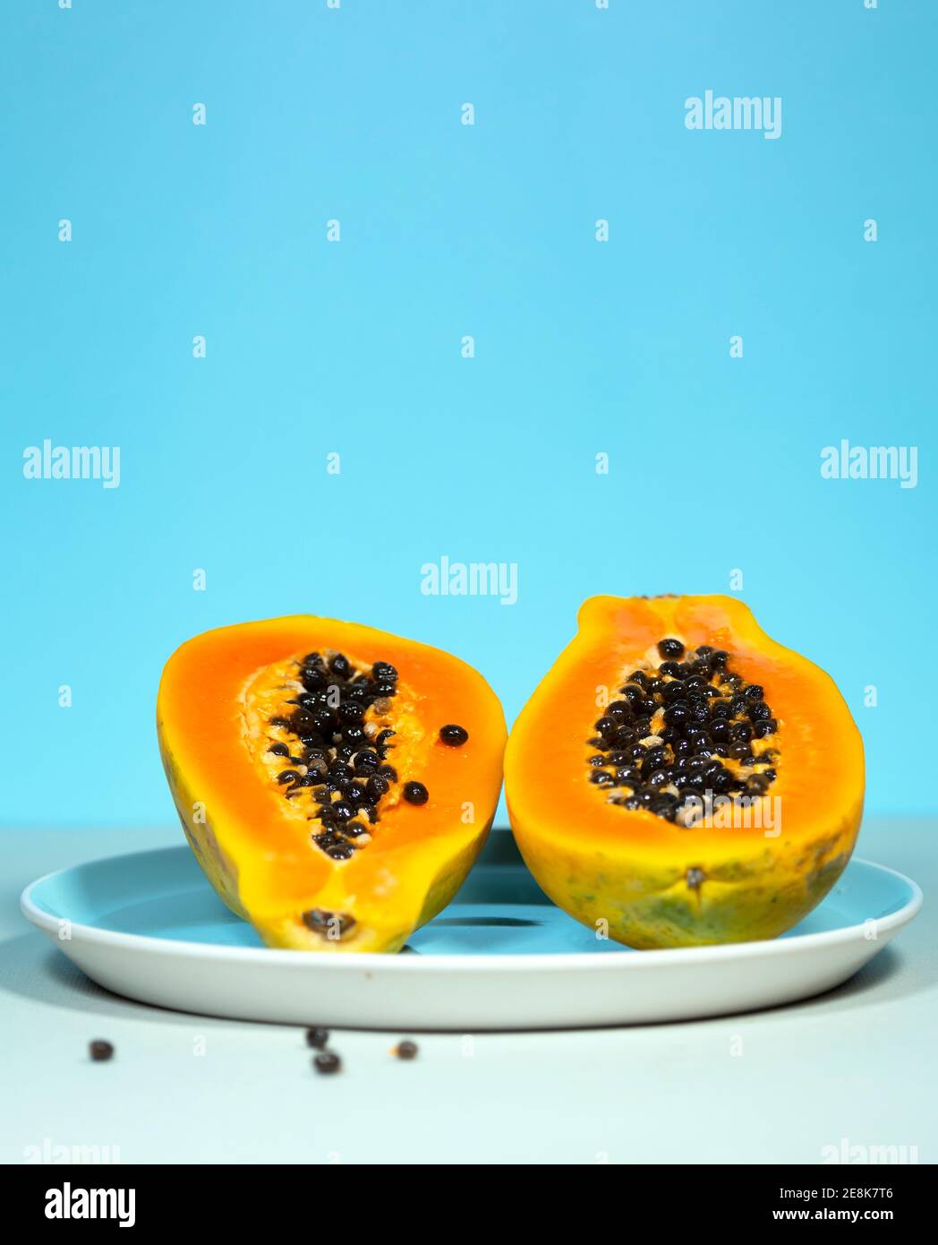 Two Half of Papaya with Green and Seeds on Blue Background, Minimalism