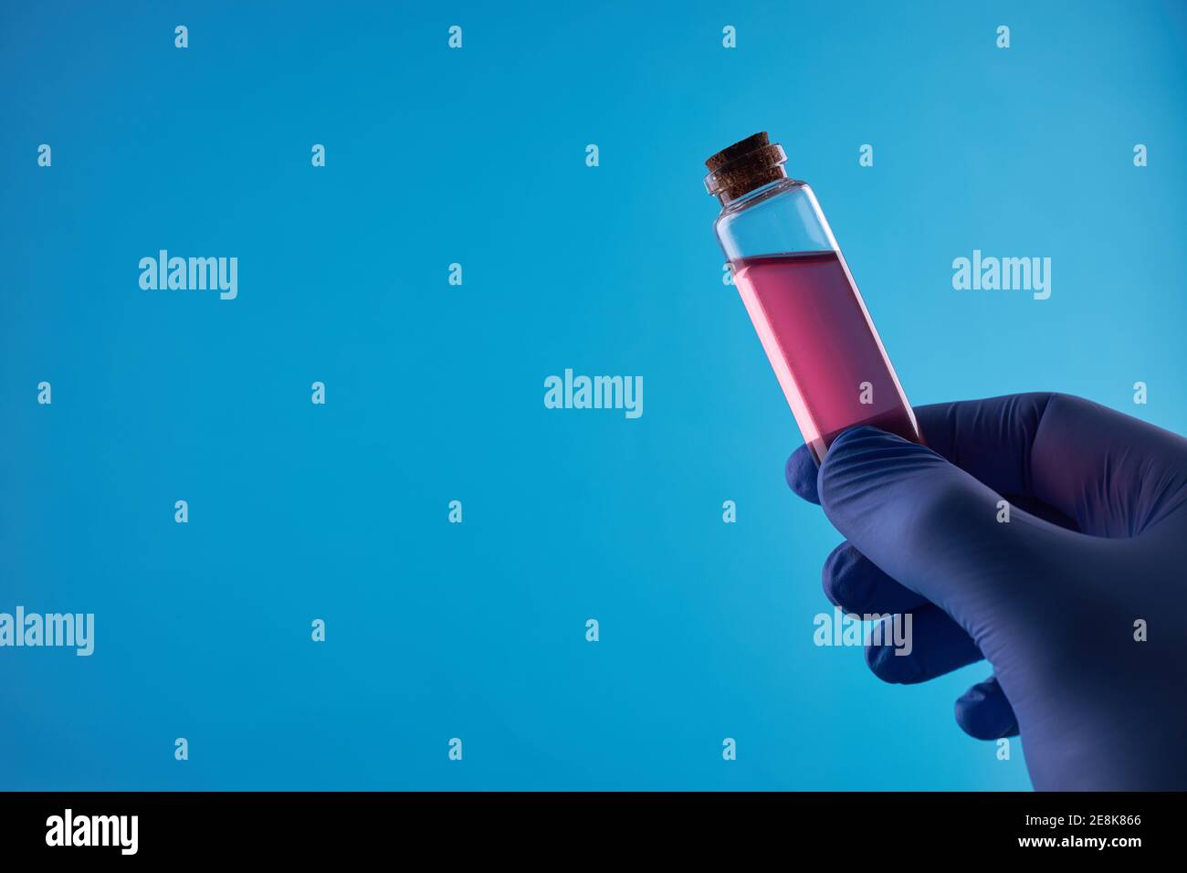 vessel with red liquid over blue background. virus and infection protection concept Stock Photo
