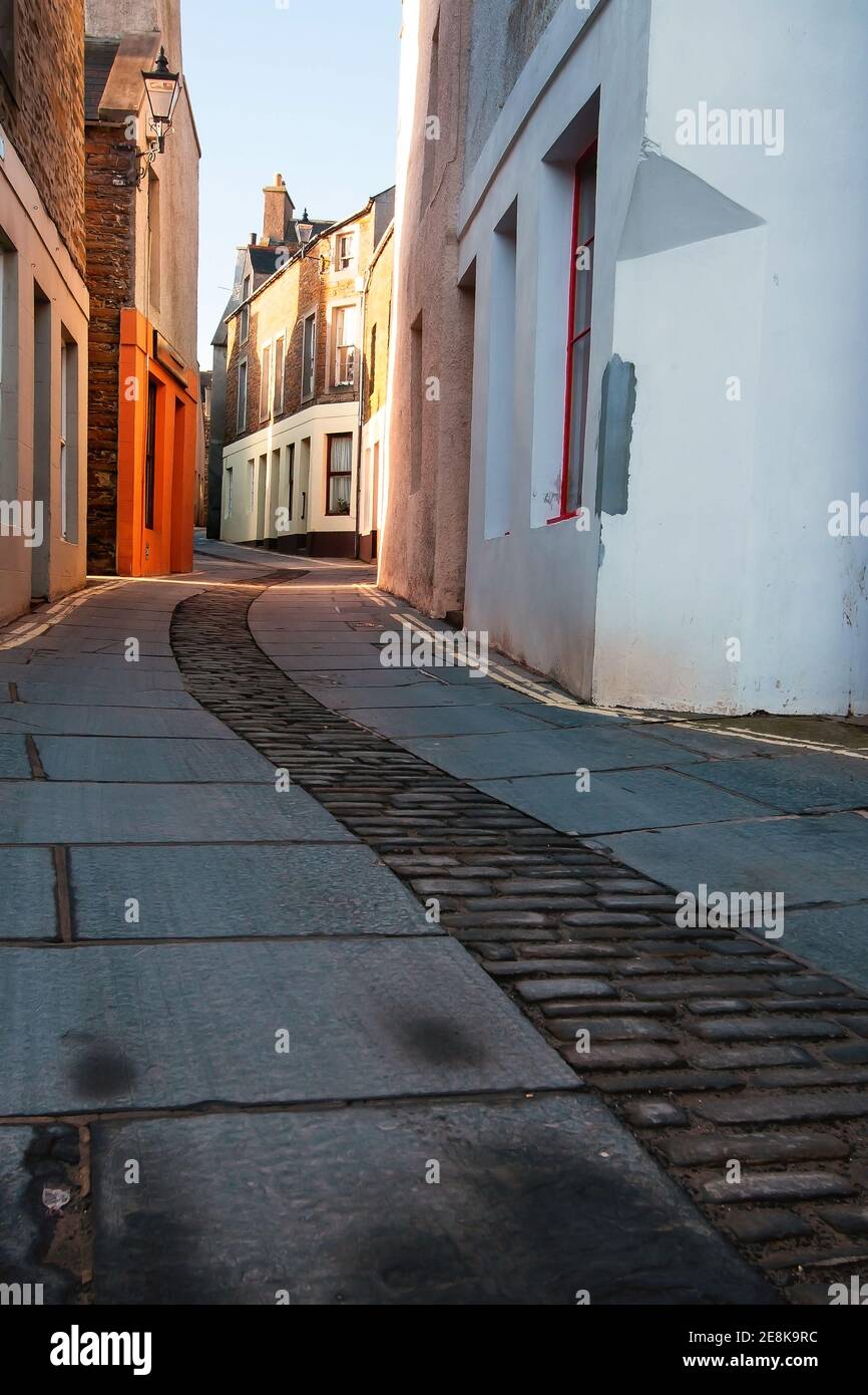 Empty narrow street in scottish town Stromness on Orkney islands taken from ground level with stone slabs and pebbles Stock Photo