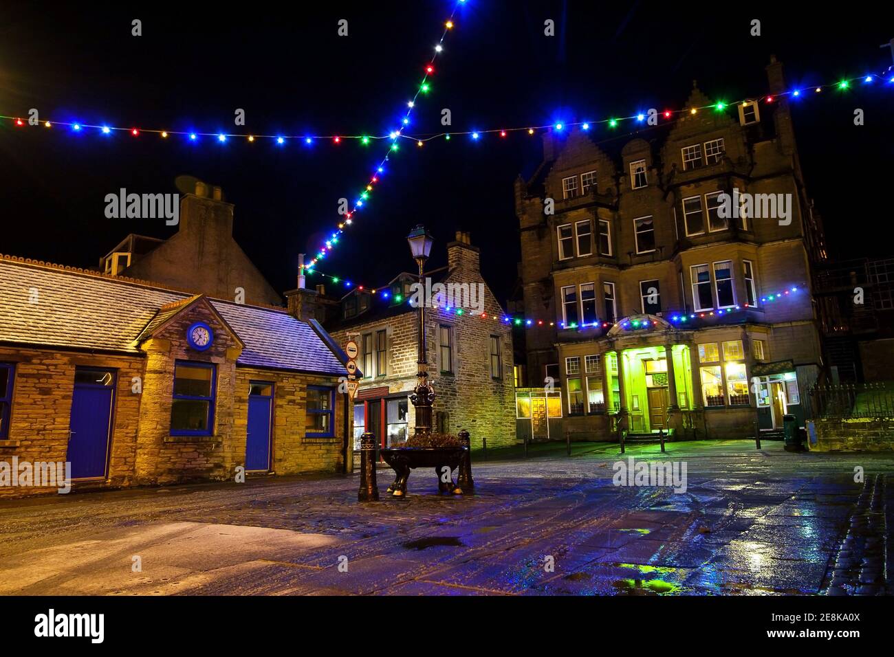 String of christmas decoration lights hanging over street in scottish town Stromness on Orkney during Christmas festive time in december winter night Stock Photo