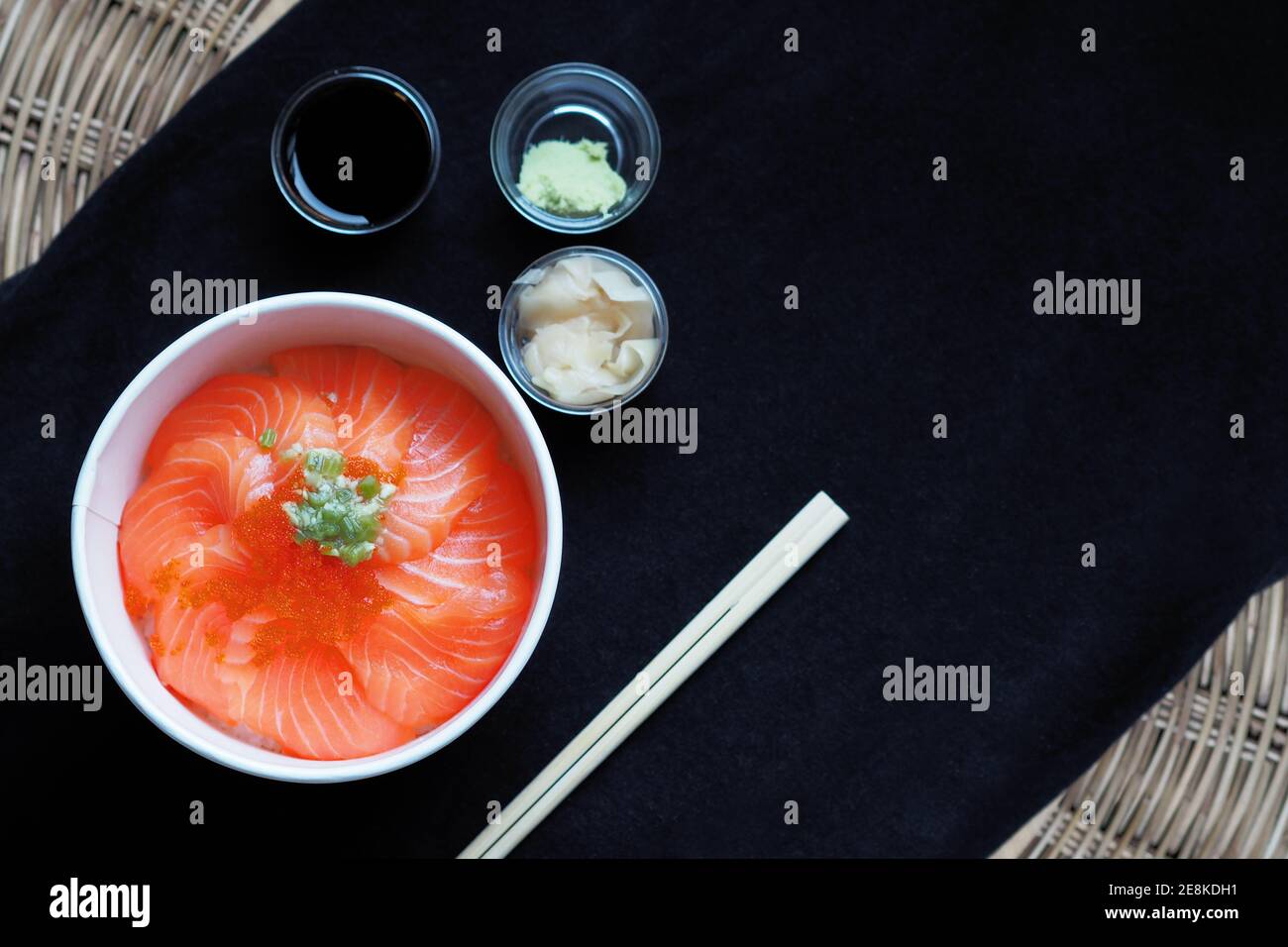 Top view and focus to Salmon with Japanese rice or Salmon Ikura Don in paper dish from delivery restaurant on black Table cloths Stock Photo