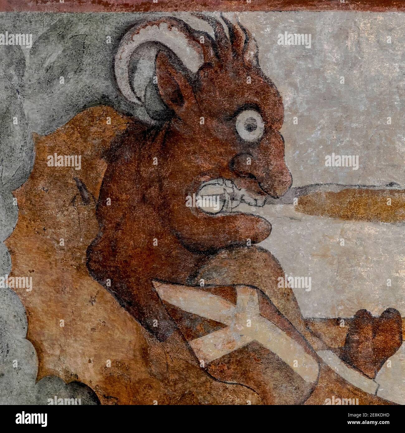 A grotesque horned demon with sabre teeth stares wideeyed as Saint