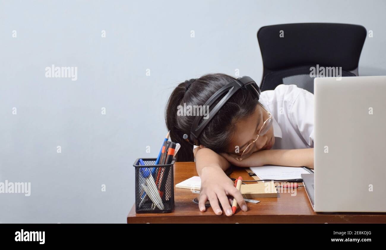 Soft focus on young student sleeping with headphone on desk at home, tired from studying online. Stock Photo