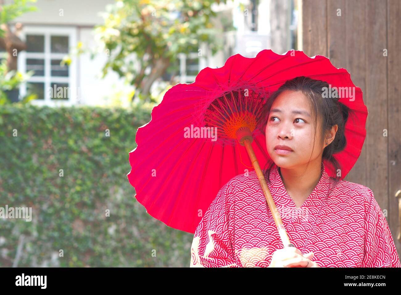 Soft focus on Traditional Japanese Yukata young girl with red umbrella in garden, Asian girl in Yukata with umbrella, Japanese tradition concept Stock Photo