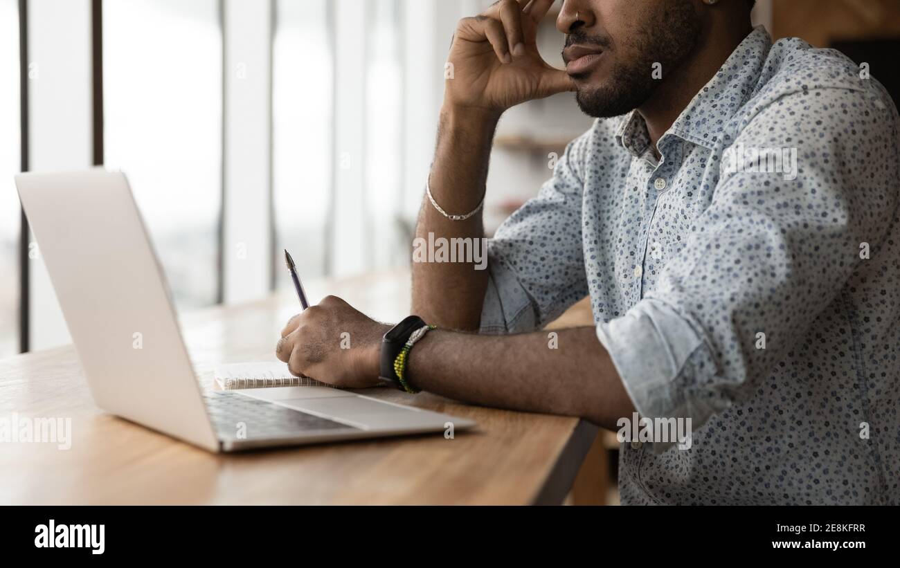 Pensive young black man sit at desk before pc screen Stock Photo