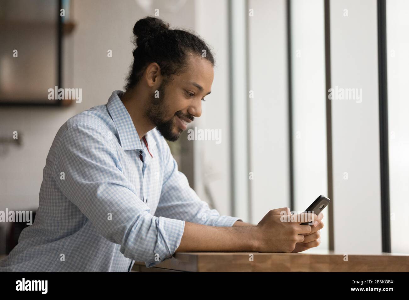 Positive young black male having pleasure playing game by cell Stock Photo