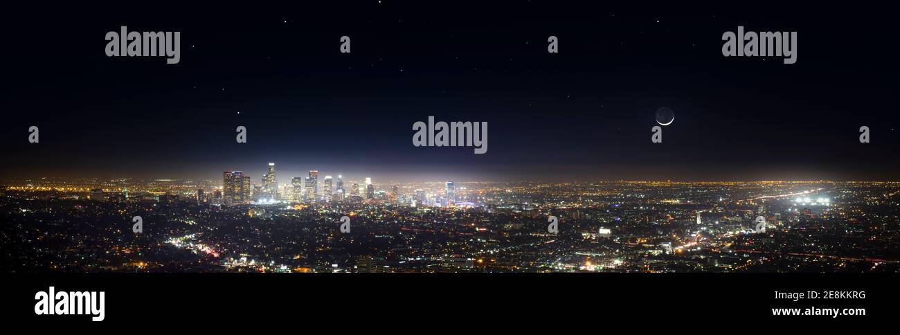 A panorama of the Los Angeles skyline with a crescent moon in the sky. Stock Photo