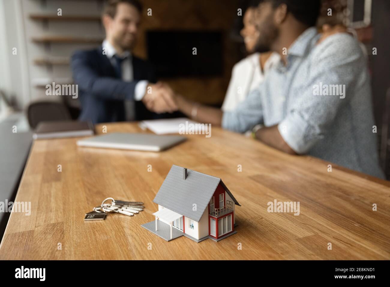 Closeup of keys and toy cottage house on wooden table Stock Photo
