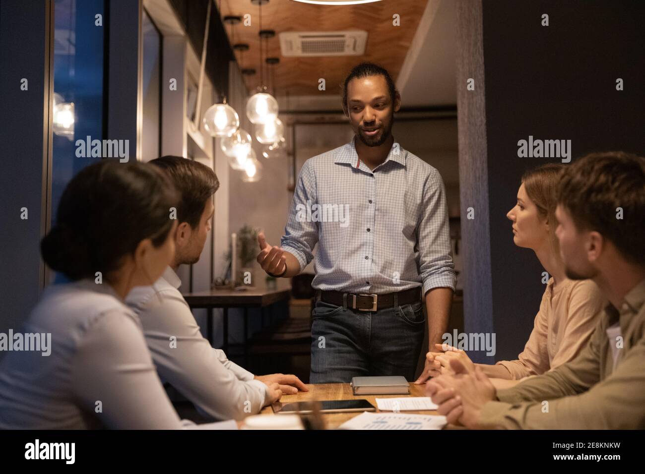 Enthusiastic young african guy present problem solution to diverse colleagues Stock Photo
