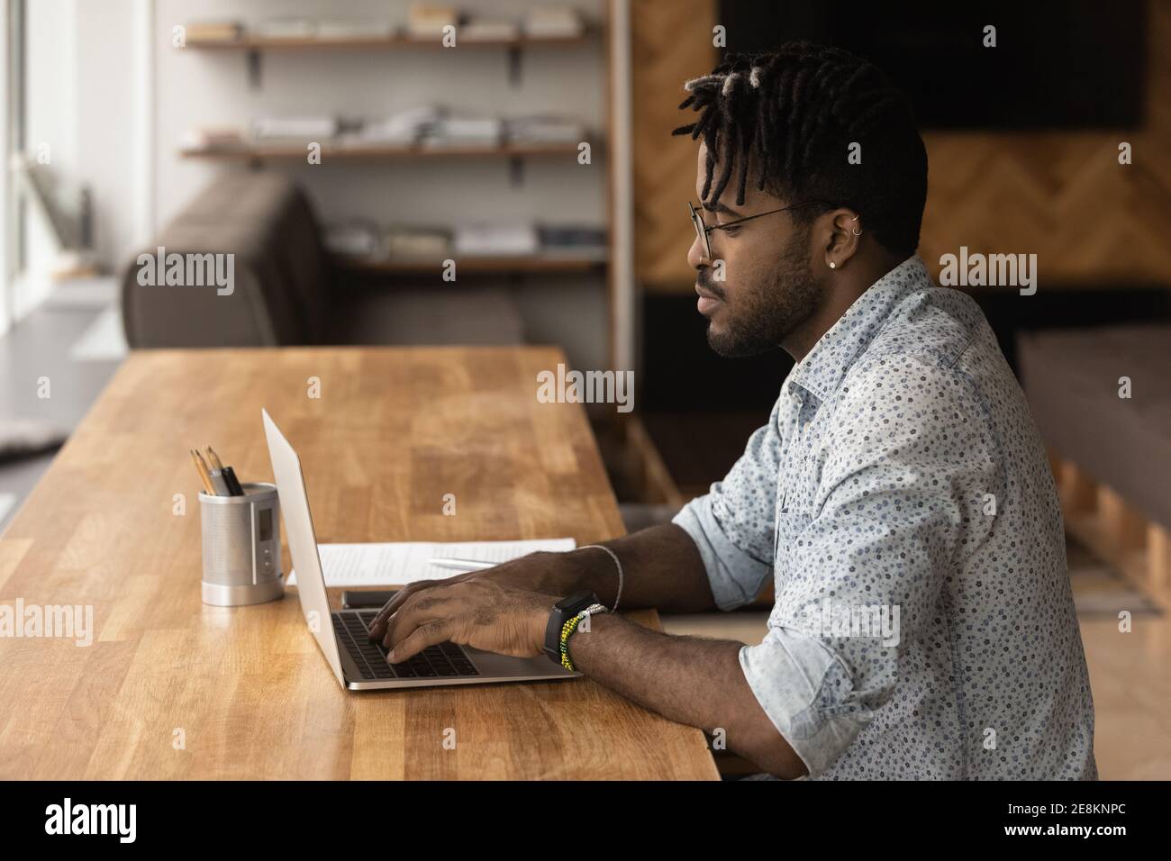 Focused black young man typing on laptop looking at screen Stock Photo