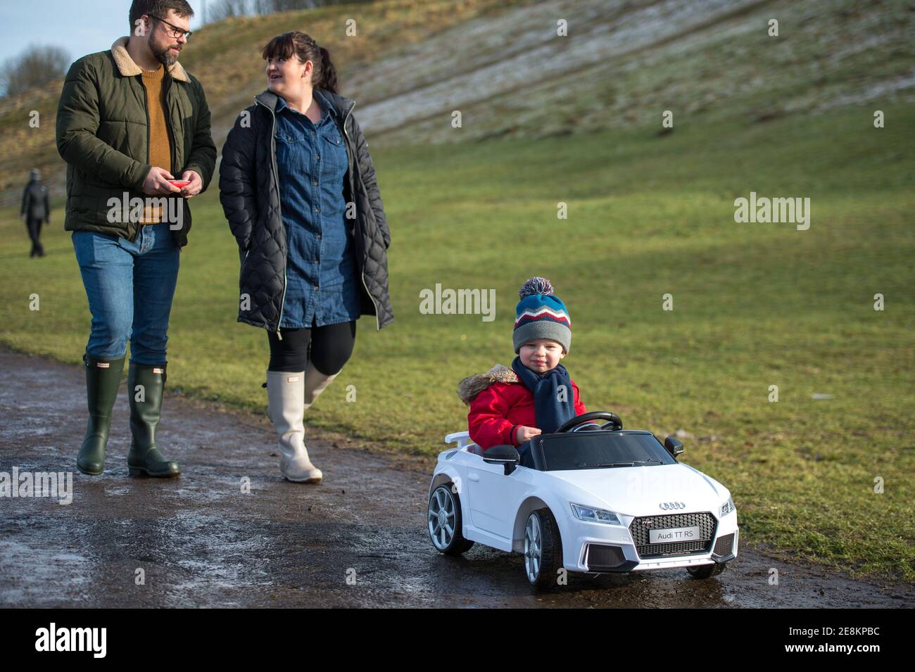 Hamilton, Scotland, UK. 31st Jan, 2021. Pictured: A young family seen walking as their kid takes in the sites from his toy convertible Audi car in the park. People out in Chatelherault Country Park taking in exercise as the temperature stays just above freezing. The sun is out and people are enjoying themselves during the coronavirus phase 4 lockdown. Credit: Colin Fisher/Alamy Live News Stock Photo
