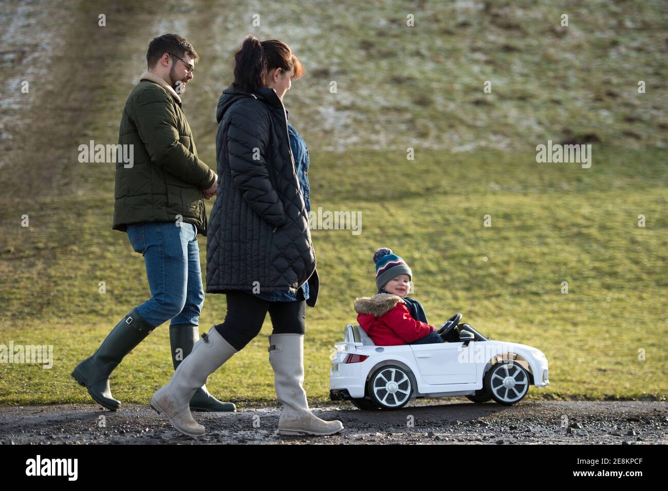 Hamilton, Scotland, UK. 31st Jan, 2021. Pictured: A young family seen walking as their kid takes in the sites from his toy convertible Audi car in the park. People out in Chatelherault Country Park taking in exercise as the temperature stays just above freezing. The sun is out and people are enjoying themselves during the coronavirus phase 4 lockdown. Credit: Colin Fisher/Alamy Live News Stock Photo