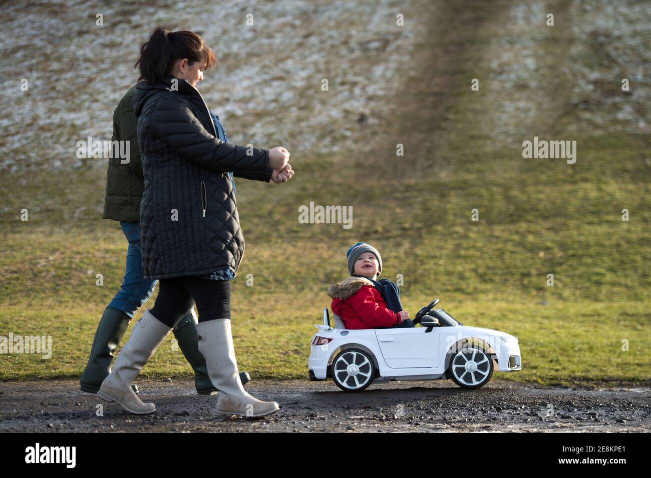 Hamilton, Scotland, UK. 31st Jan, 2021. Pictured: A young family seen walking as their kid takes in the sites from his toy convertible Audi car in the park. People out in Chatelherault Country Park taking in exercise as the temperature stays just above freezing. The sun is out and people are enjoying themselves during the coronavirus phase 4 lockdown. Credit: Colin Fisher/Alamy Live News Stock Photo