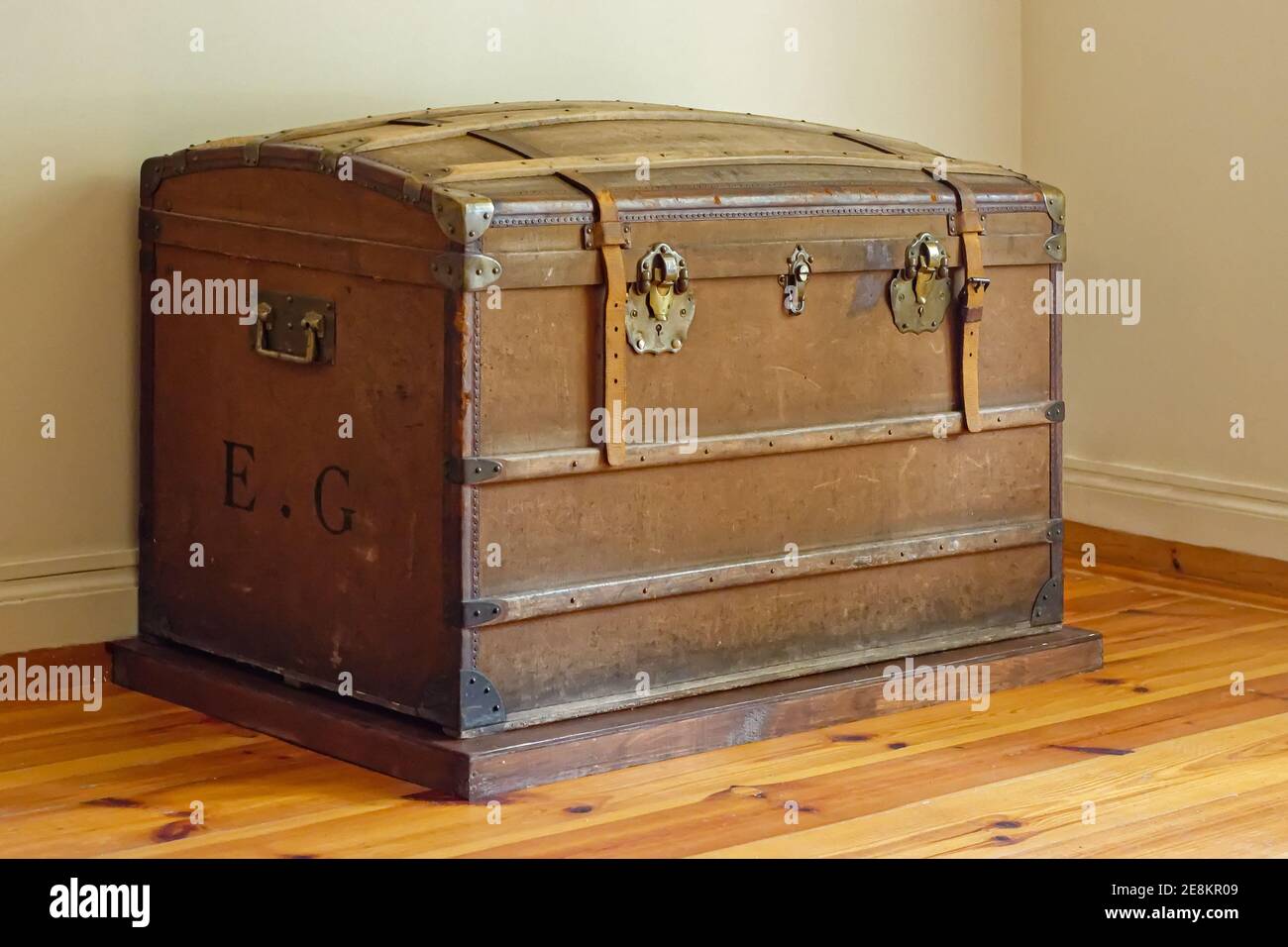 Old leather chest with iron brackets in the corner of the room. Stock Photo