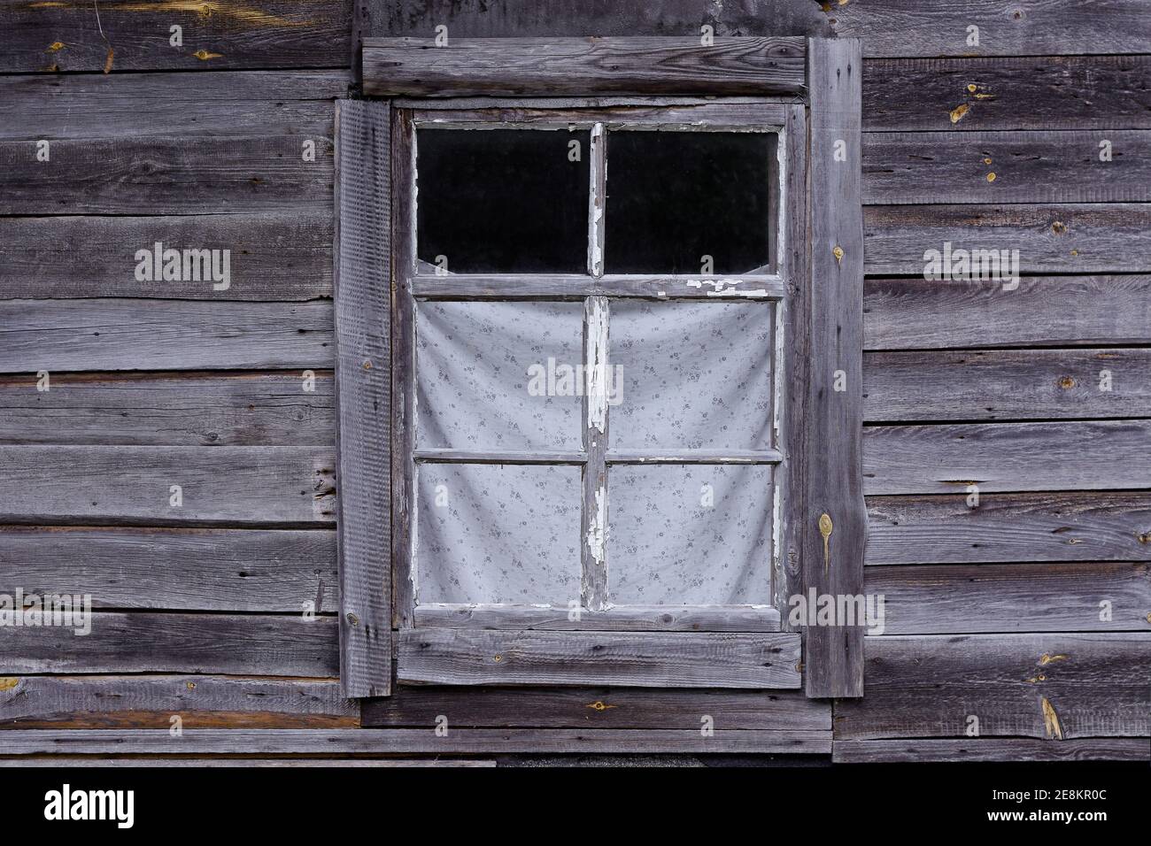 Rectangular window with a white frame in an old country house against a wall of gray wooden planks. From the window of the world series. Stock Photo