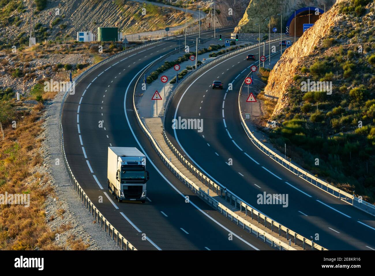 Highway at the exit of a tunnel with a truck and several cars circulating. Stock Photo