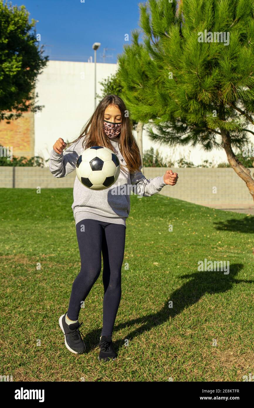 Beautiful little girl playing soccer in a nice park with natural grass ...