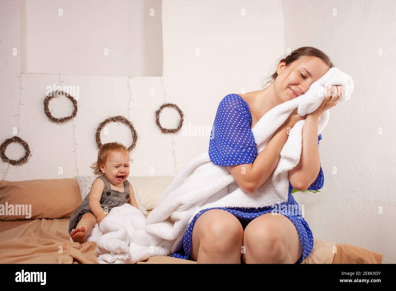 Mom imagines a sweet dream without a baby. The baby screams, hysterical. The woman wants to sleep and take a break from the baby. Dreams of rest from Stock Photo