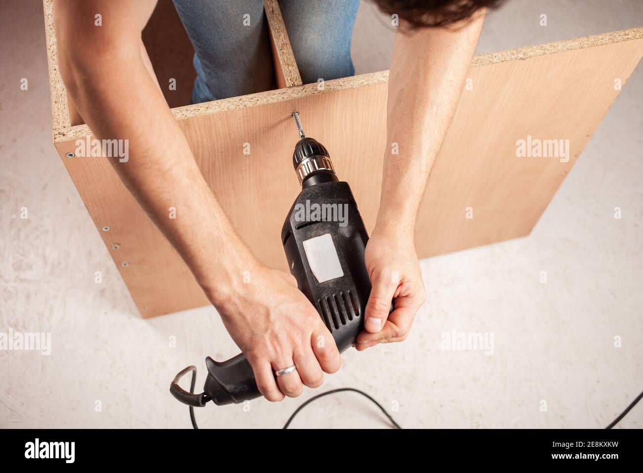 A man drills a hole in a closet. Stock Photo