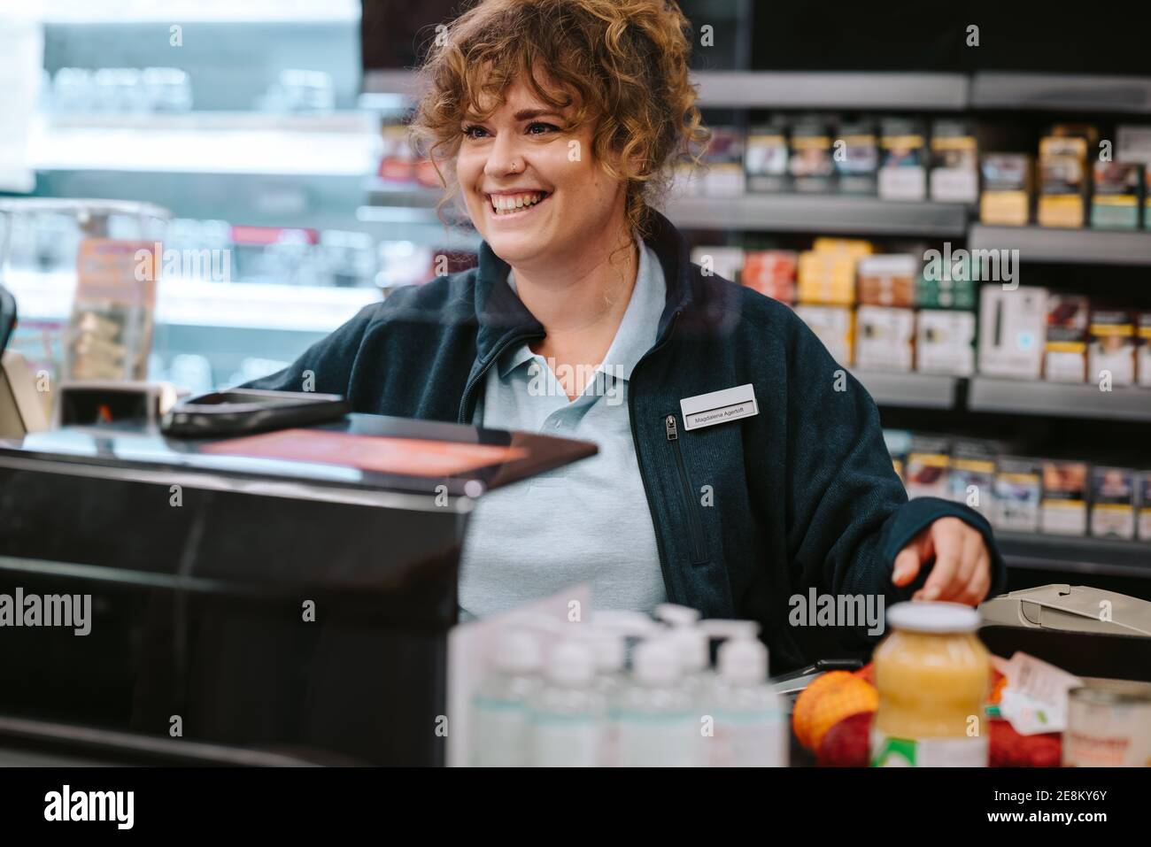 Female grocery store manager working at checkout counter. Woman cashier working at supermarket checkout. Stock Photo