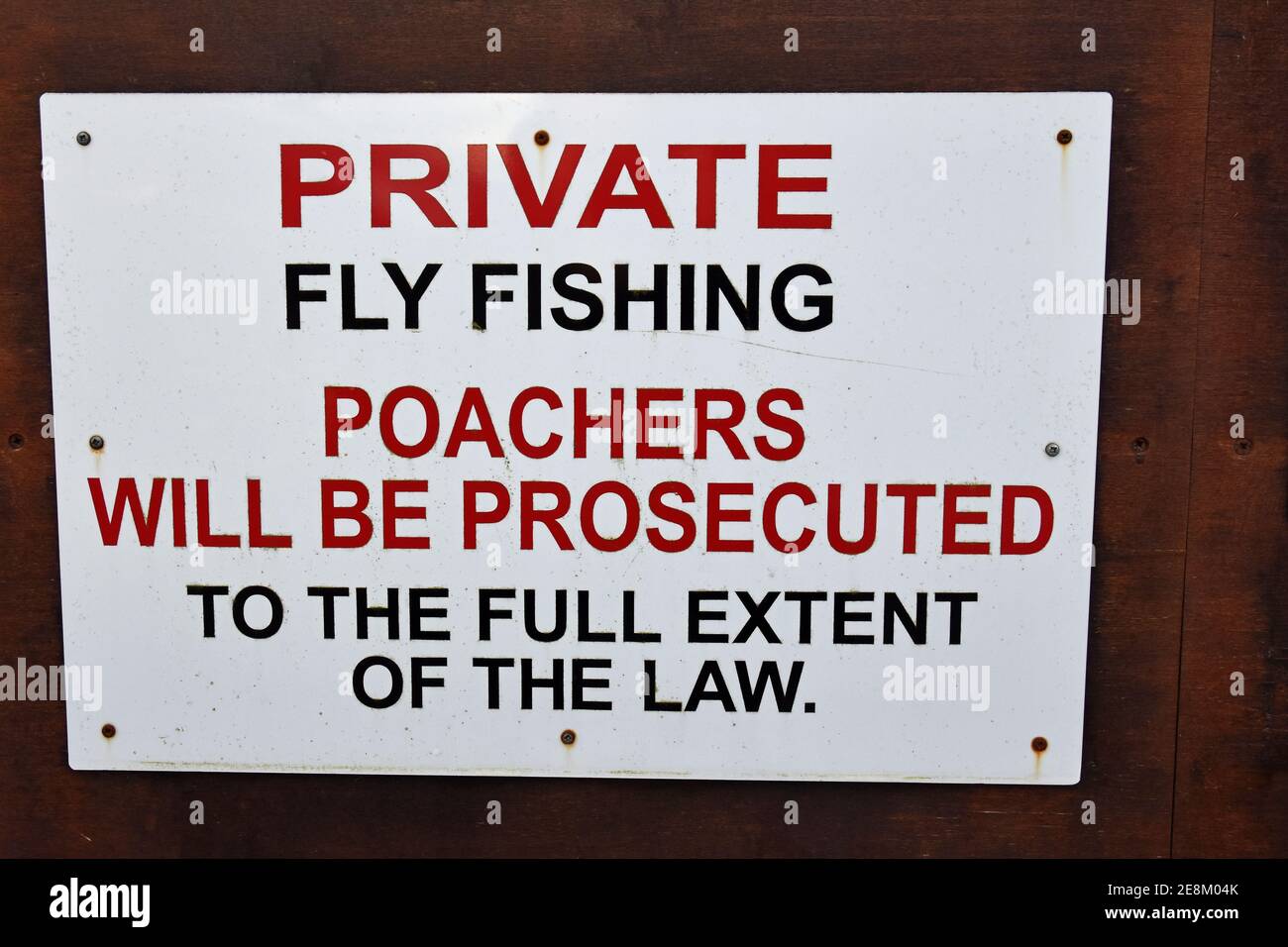 Rectangular sign private fly fishing poachers will be prosecuted to the full extent of the wall. Isolated on dark background, Stock Photo