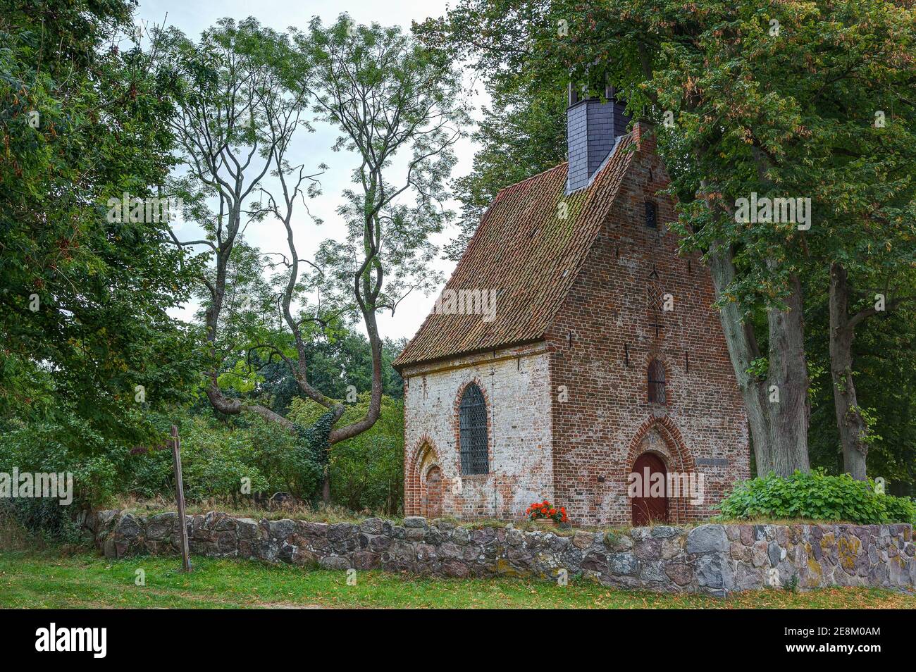 Small old church, idyllically situated on the edge of the village, surrounded by a natural stone wall. Stock Photo