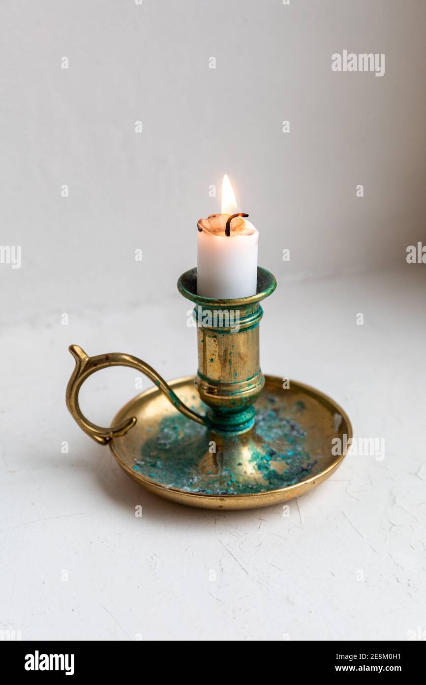 Burning candle stub in a brass candlestick or candleholder with patina or verdigris Stock Photo