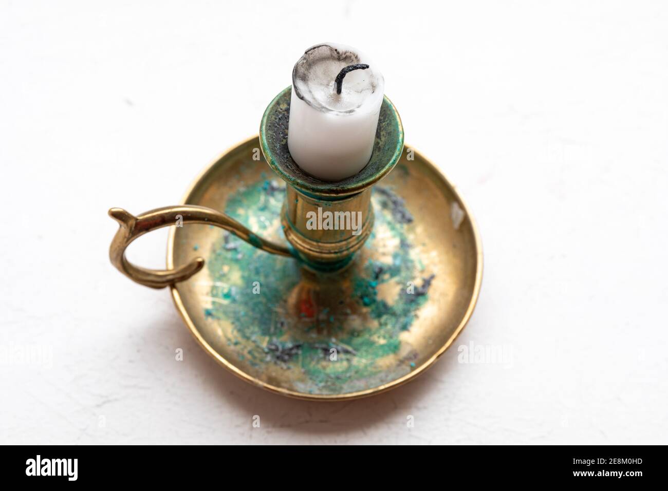 Candle stub on a brass candleholder or candlestick with green patina or verdigris Stock Photo