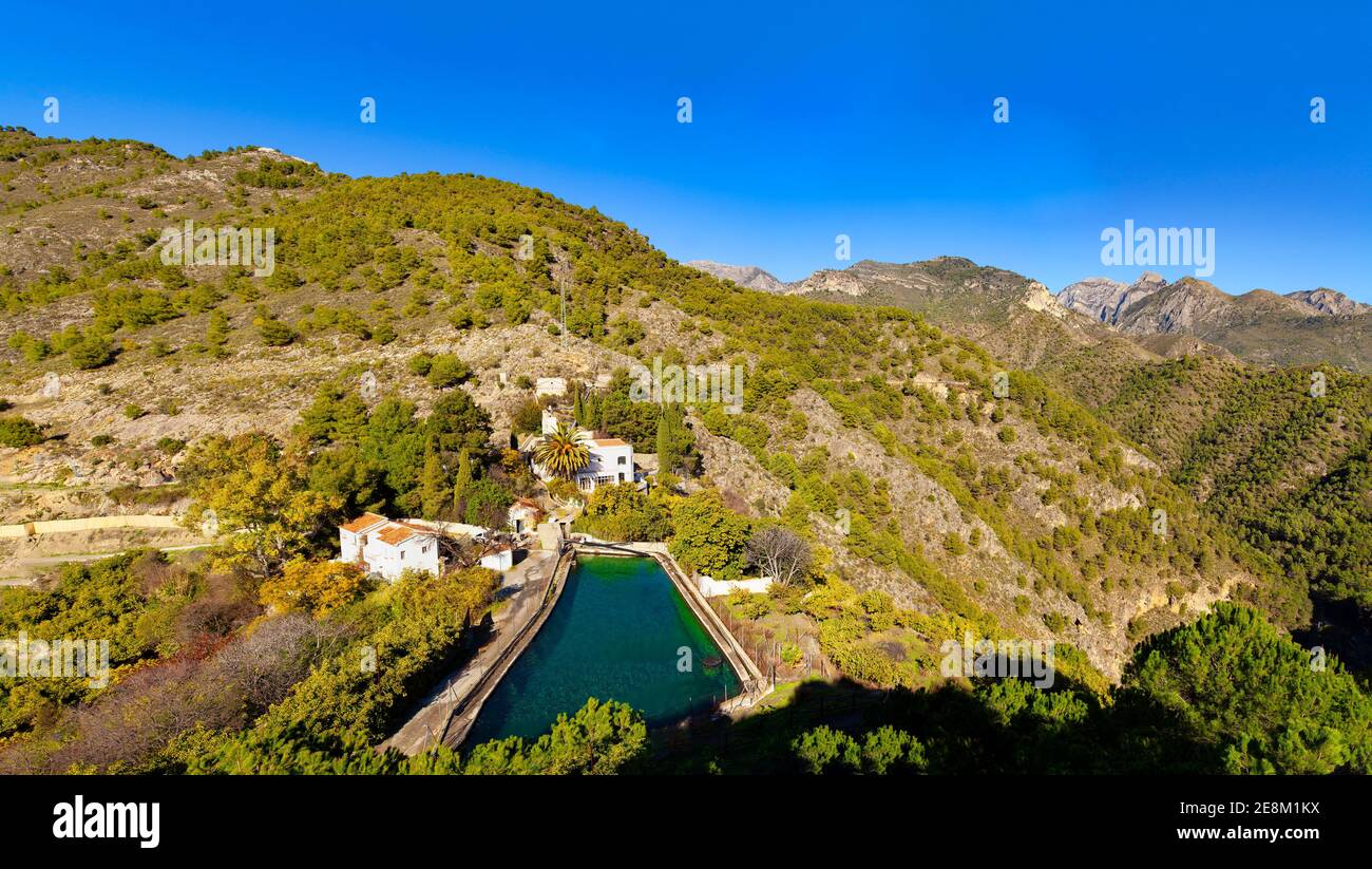 Small reservoir in the Sierra de Tejeda mountain range rising above the Chillar Valley behind Frigiliana in the province of Malaga, Andalusia, Spain Stock Photo