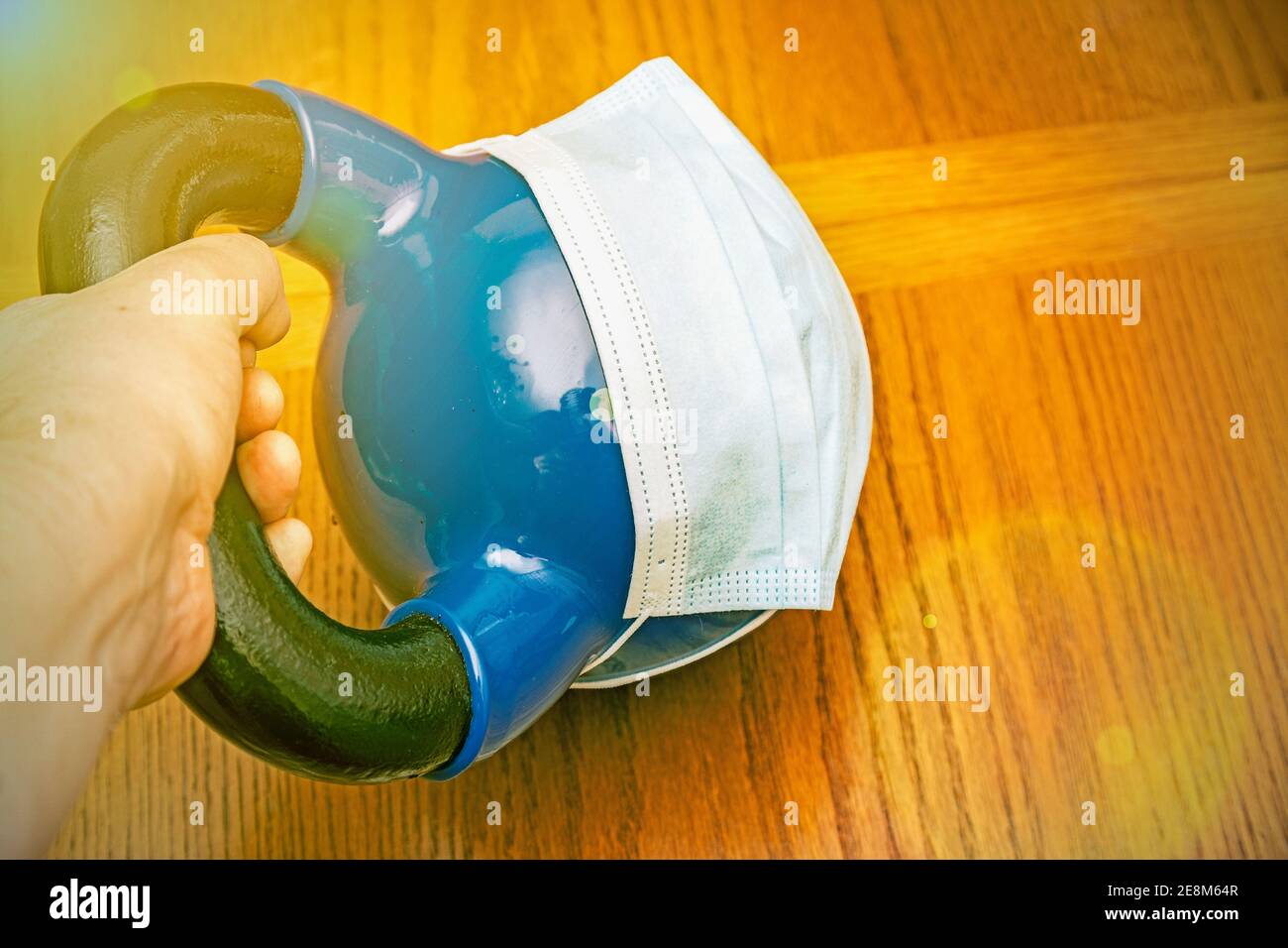 kettlebells on gym with blue surgical mask. Close up. Sports kettlebell in the gym, top view. kettlebell wearing blue medical mask. toned Stock Photo