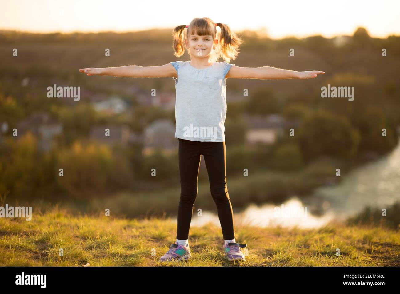 Child girl do sport exercises outdoor at sunset Stock Photo