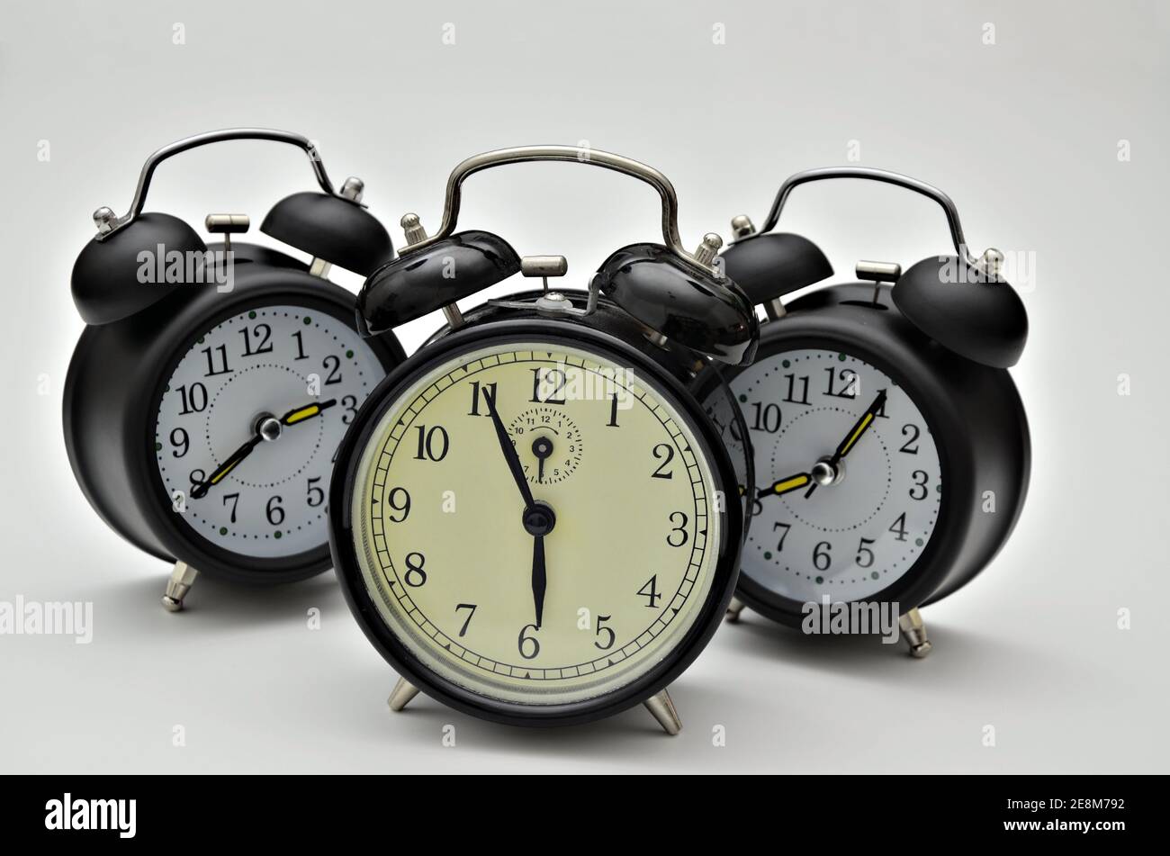 close up of three black retro alarm clocks with twin bells, showing