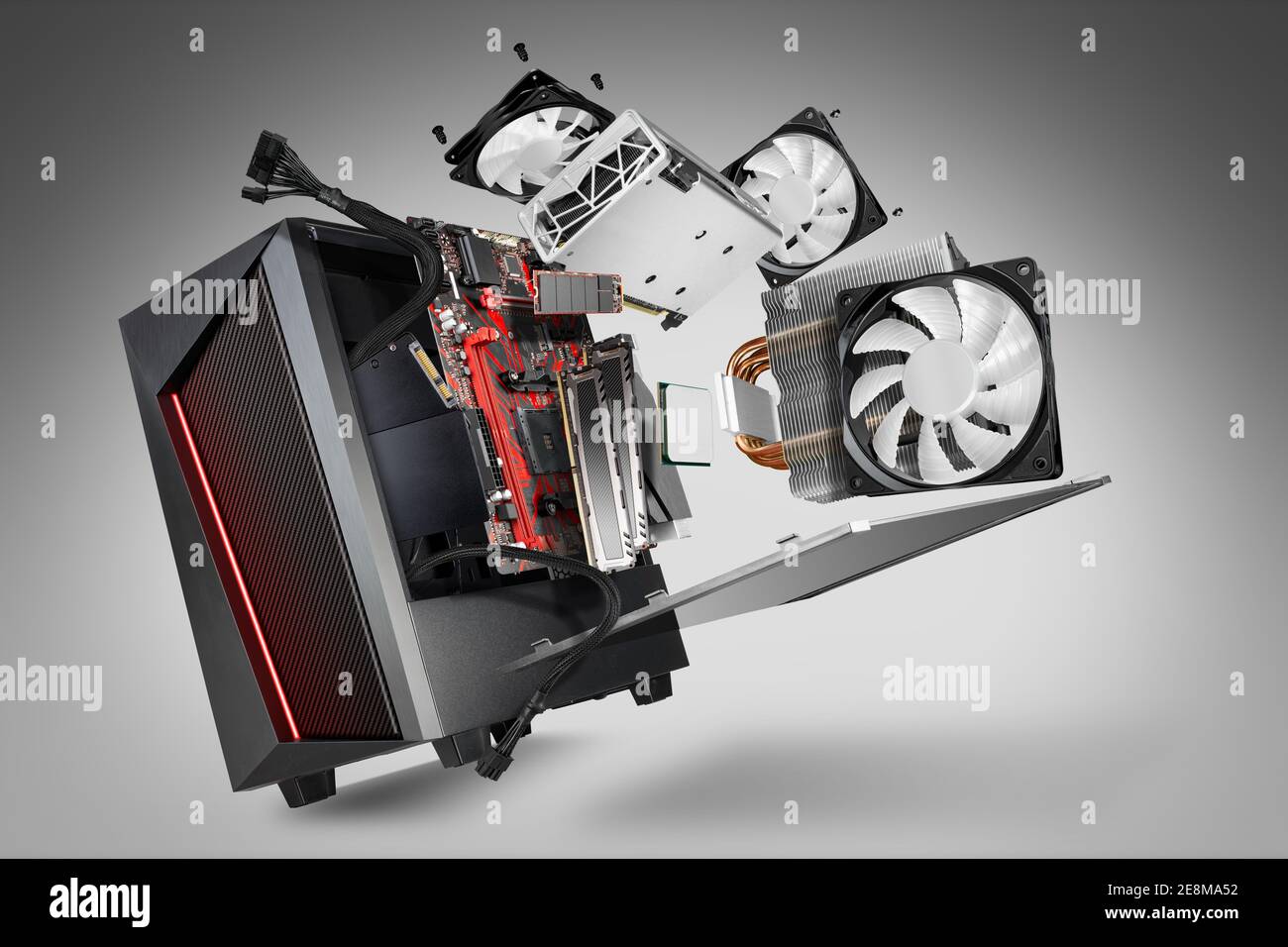 exploded view of a modern computer. hardware components mainboard cpu processor graphic card RAM cables and cooling fan flying out of black red PC cas Stock Photo