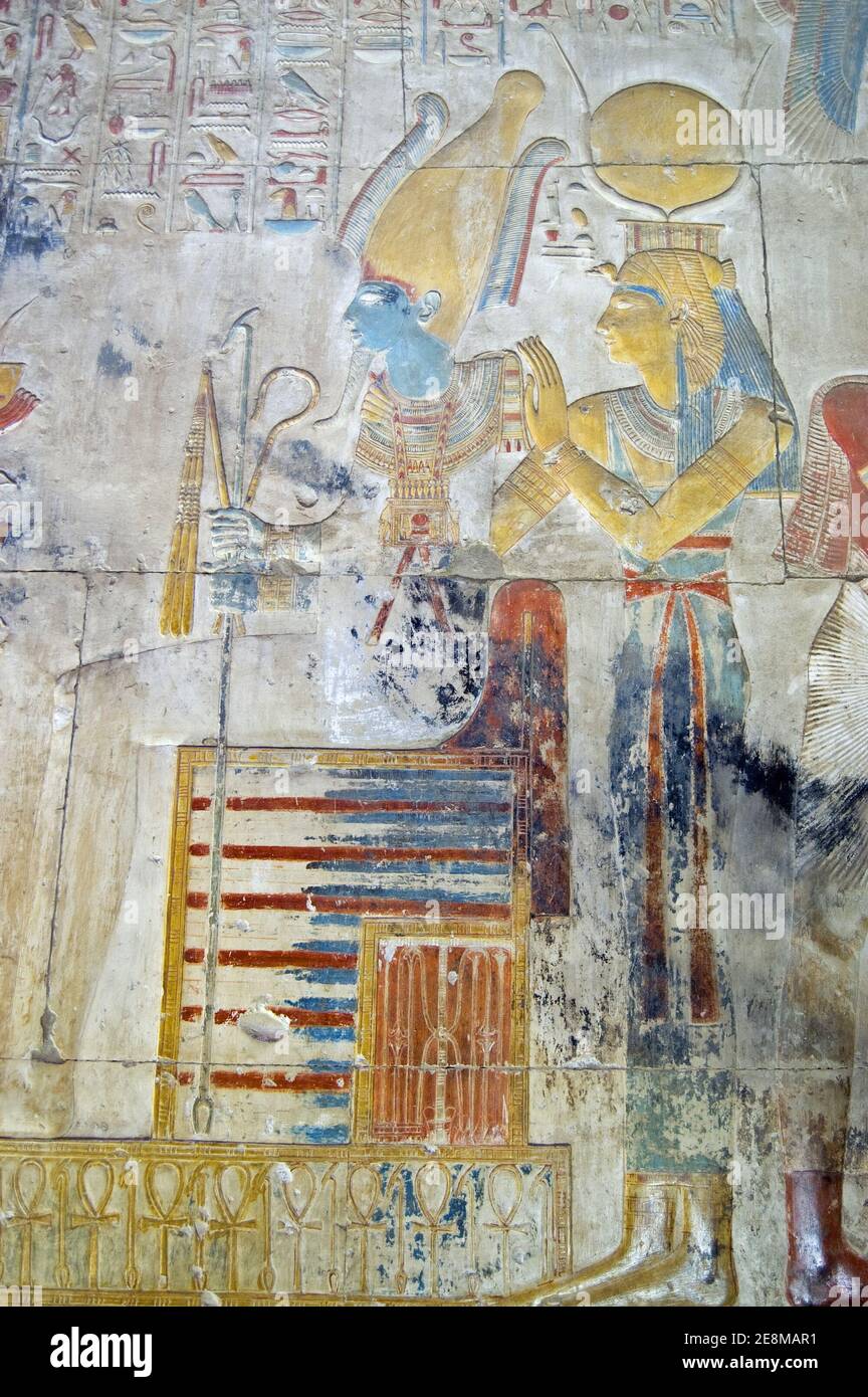 Ancient Egyptian bas relief showing the god of the underworld Osiris sitting on a a throne with his wife Isis standing behind. Abydos Temple, Egypt. O Stock Photo