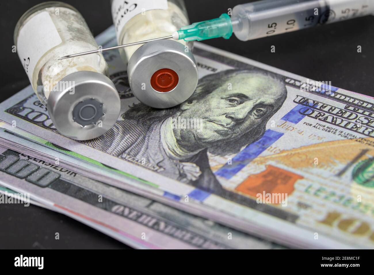 Pandemic Concept and money ( dollar) to Vaccinate. Vaccine Bottle with Syringe for Covid-19 Stock Photo