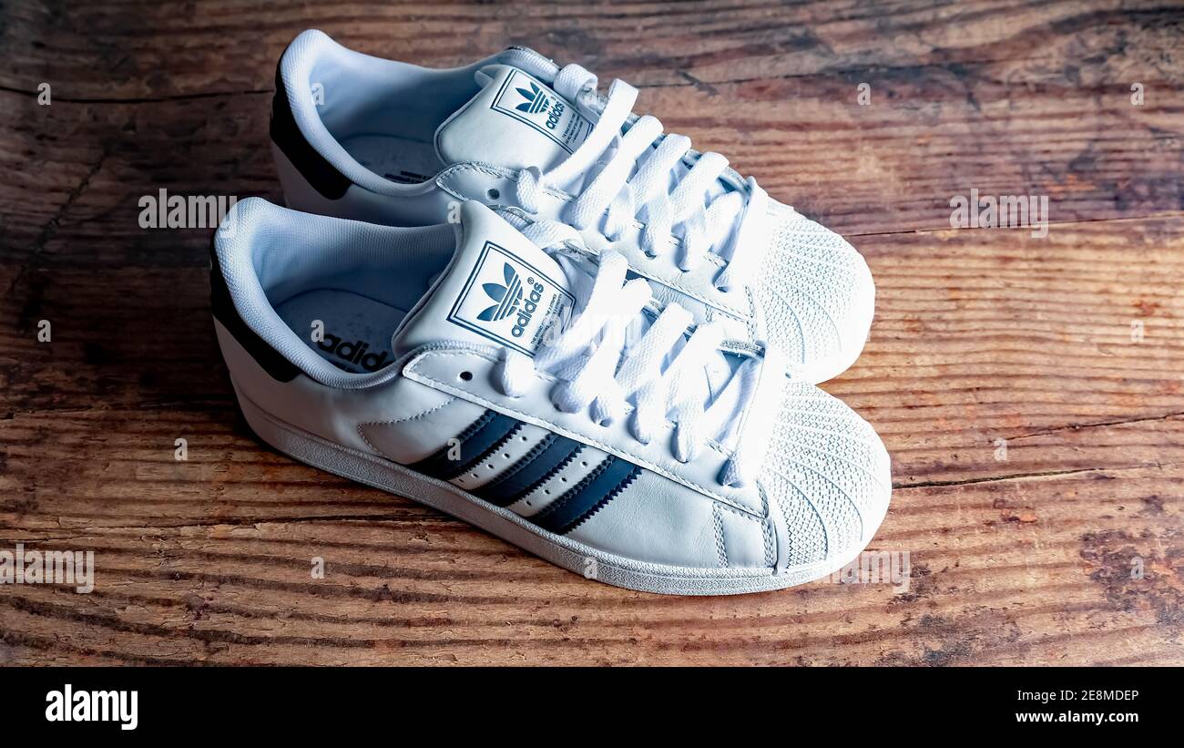 Norwich, Norfolk, UK – December 19 2020. An illustrative photo of a pair of  retro styled Adidas trainers in white with blue stripes on a wooden floor  Stock Photo - Alamy