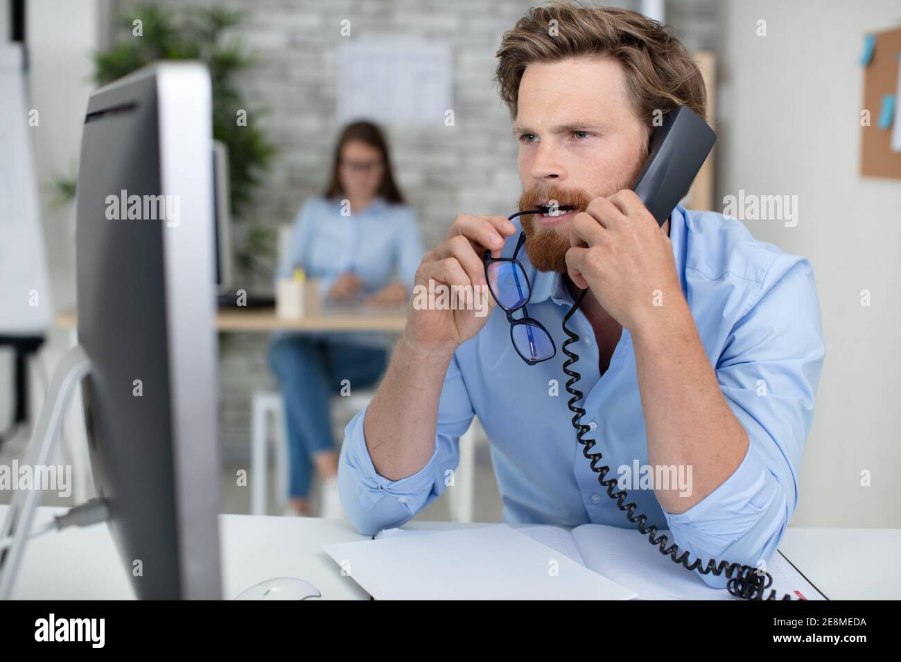 male office worker chewing his glasses while concentrating Stock Photo Alamy