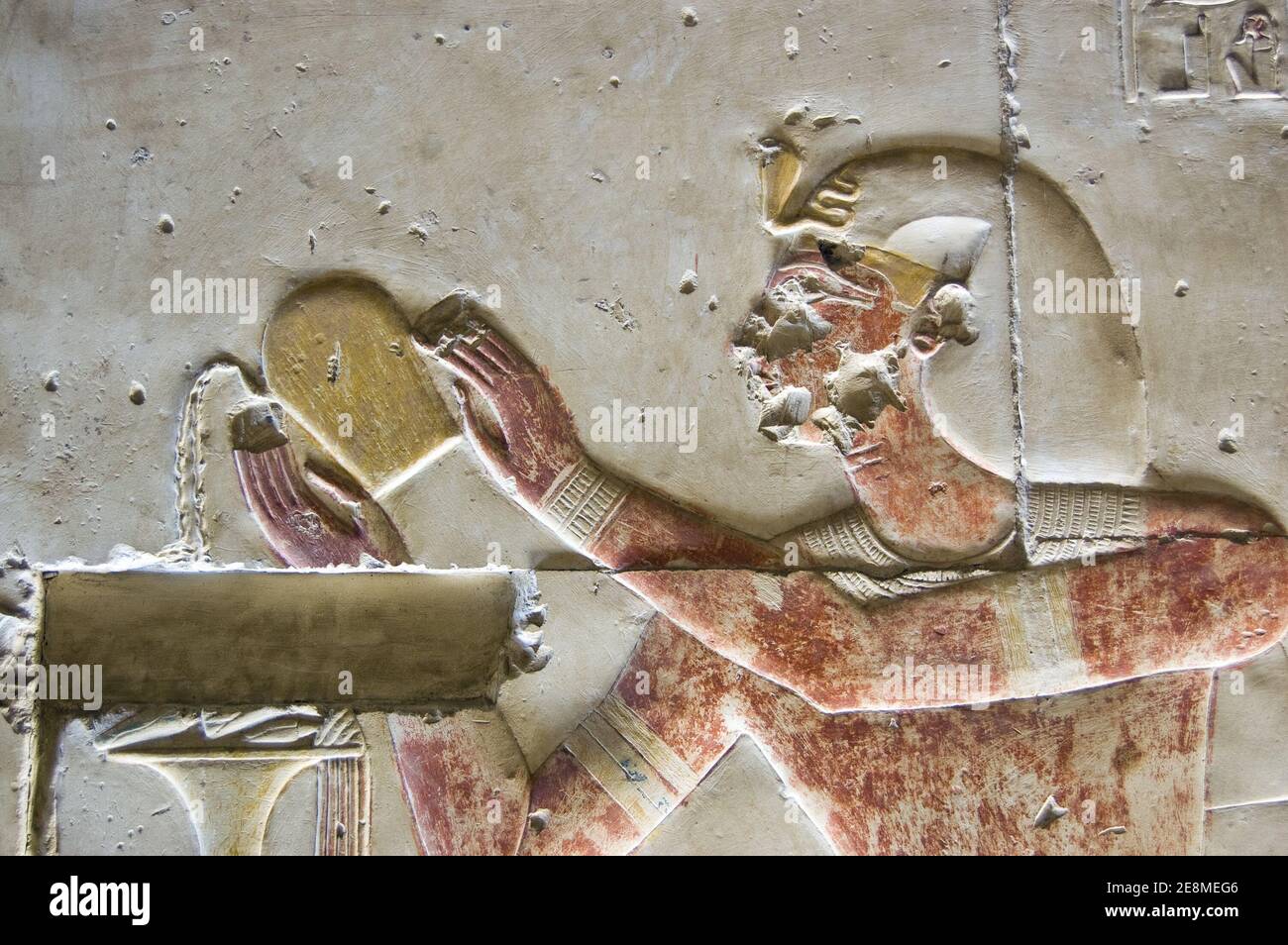 Ancient Egyptian bas relief showing Pharaoh Seti I pouring liquid, probably wine, as an offering to the god Osiris. Temple of Abydos, Egypt. Ancient c Stock Photo
