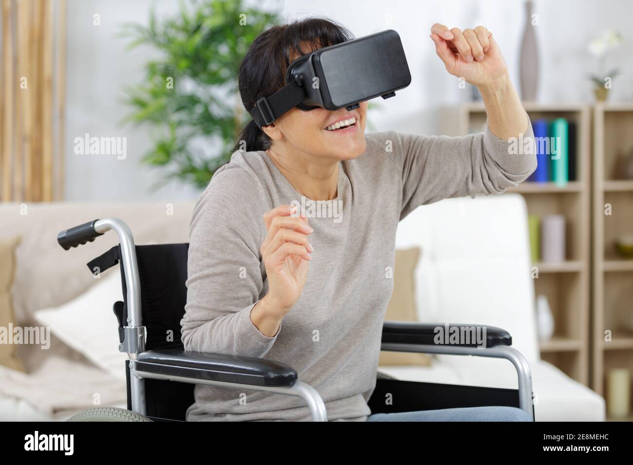 disabled woman in a wheelchair at home uses vr helmet Stock Photo - Alamy