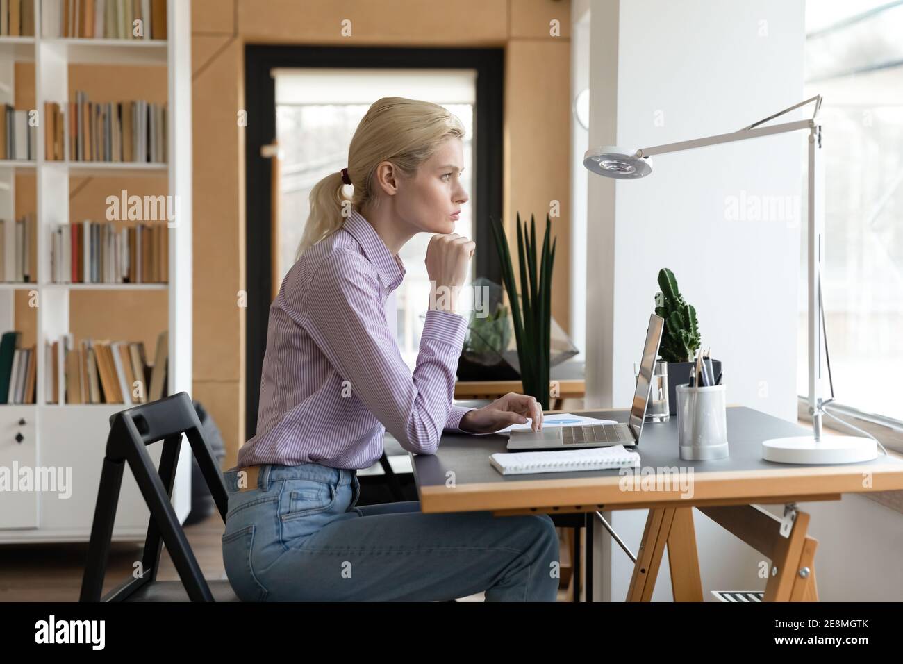 Pensive female entrepreneur looking at window and thinking Stock Photo