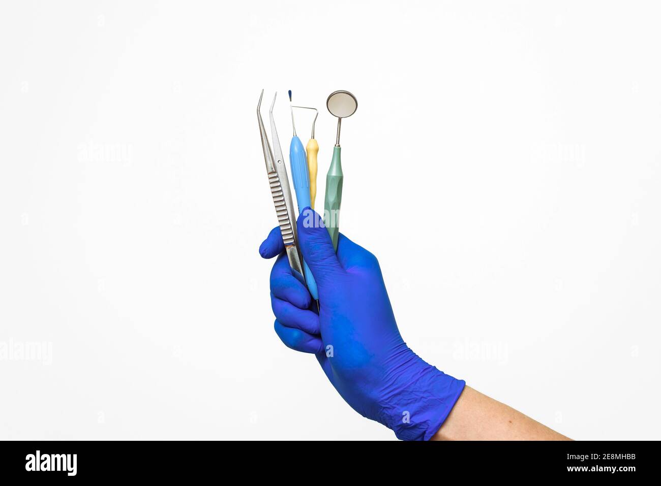The dentist's hand in a blue glove holds dental instruments ...