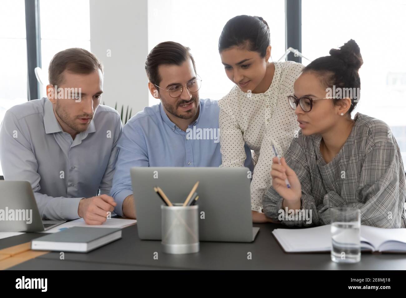 Diverse office people meeting and using shared laptop Stock Photo