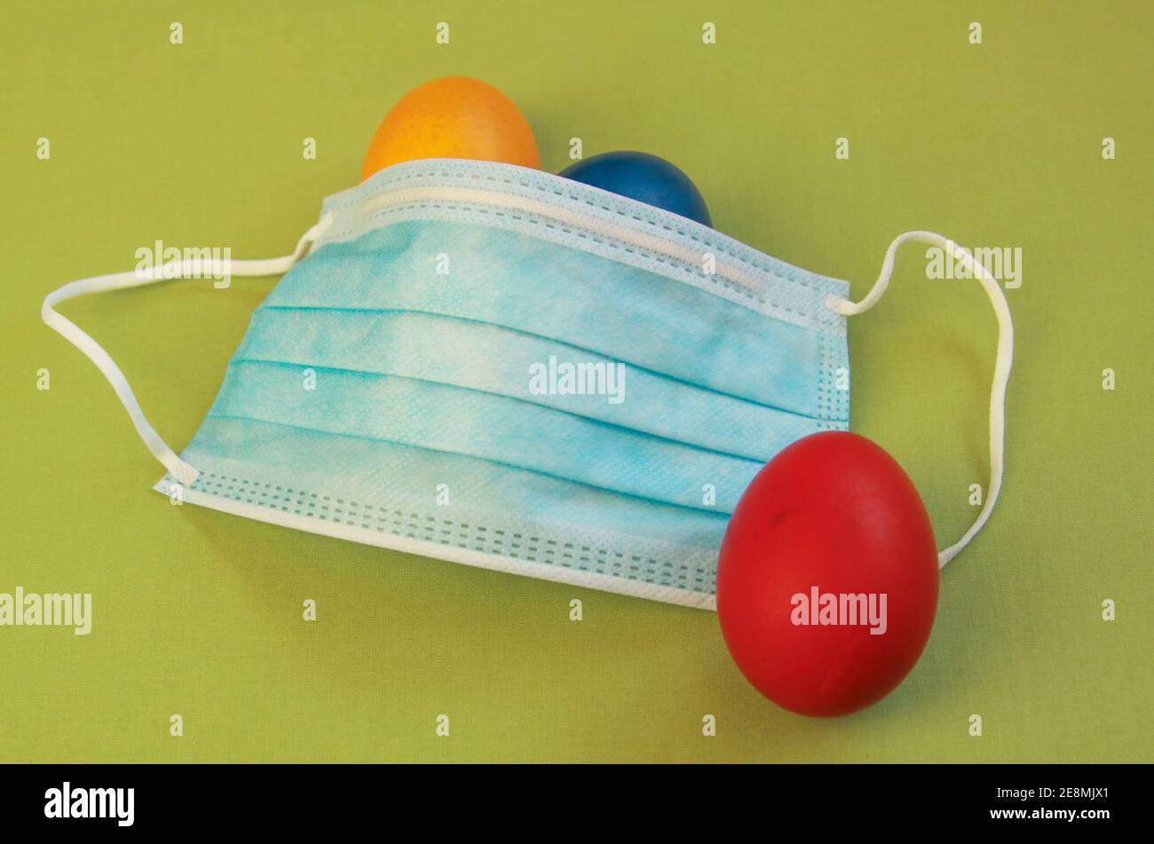 Isolated colored painted Easter eggs and medical mask, a symbol of coronavirus pandemic. Safety first while celebrating Easter 2020 covid 19 outbreak Stock Photo