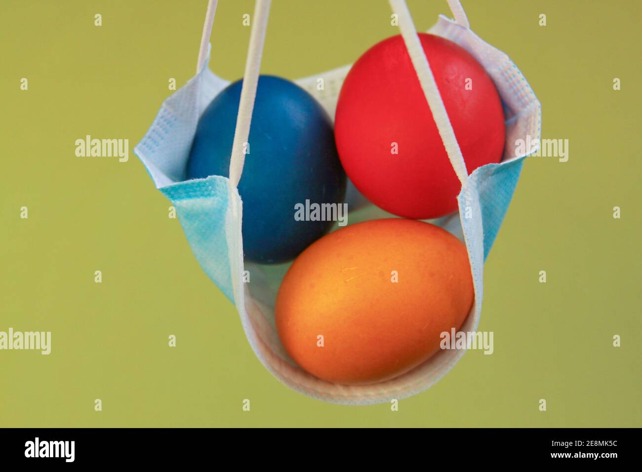Isolated colored painted Easter eggs in surgical mask, a symbol of coronavirus pandemic. Safety first while celebrating Easter 2020 covid 19 outbreak Stock Photo