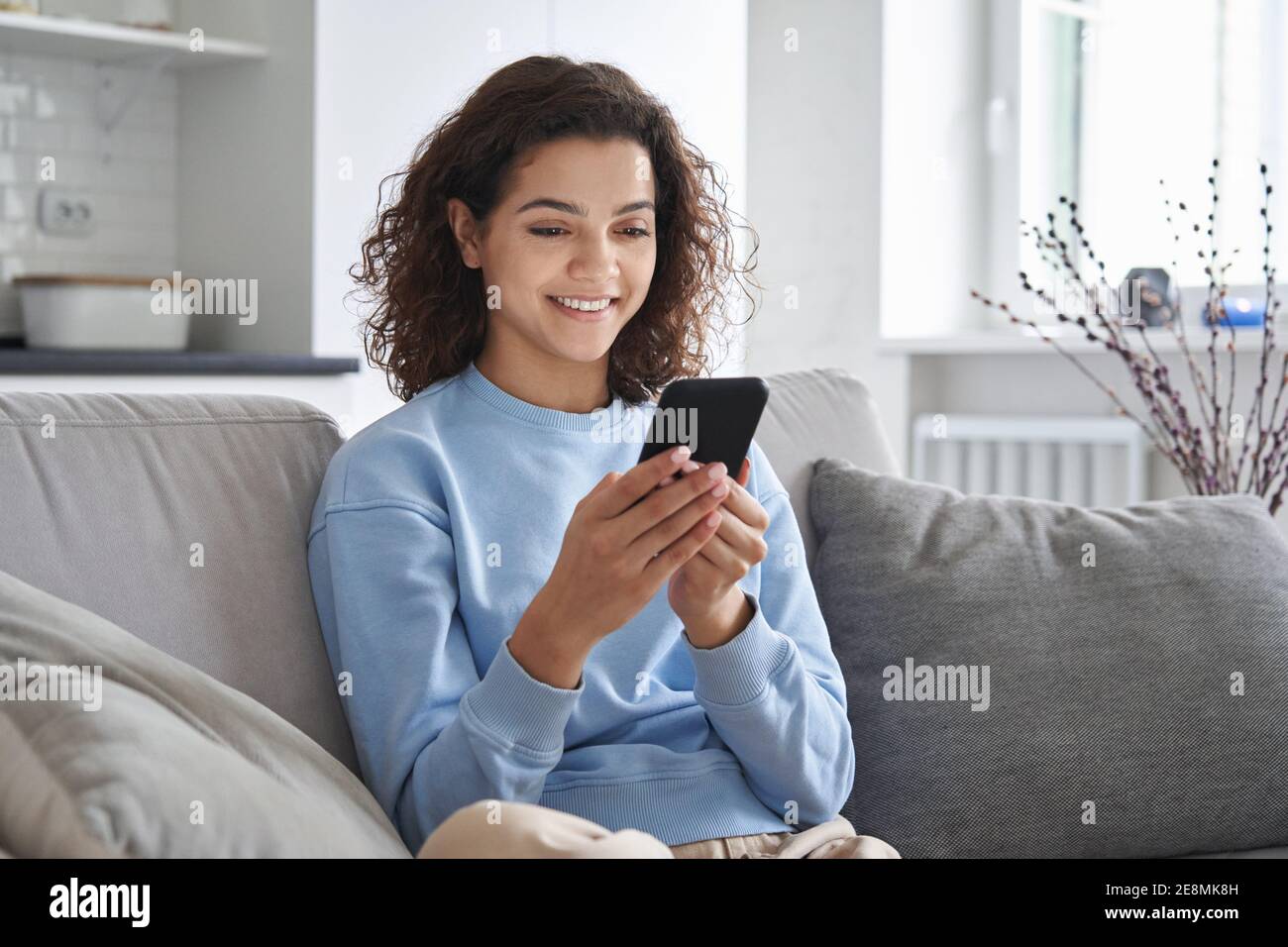 Happy hispanic teen girl holding cell phone using smartphone at home ...
