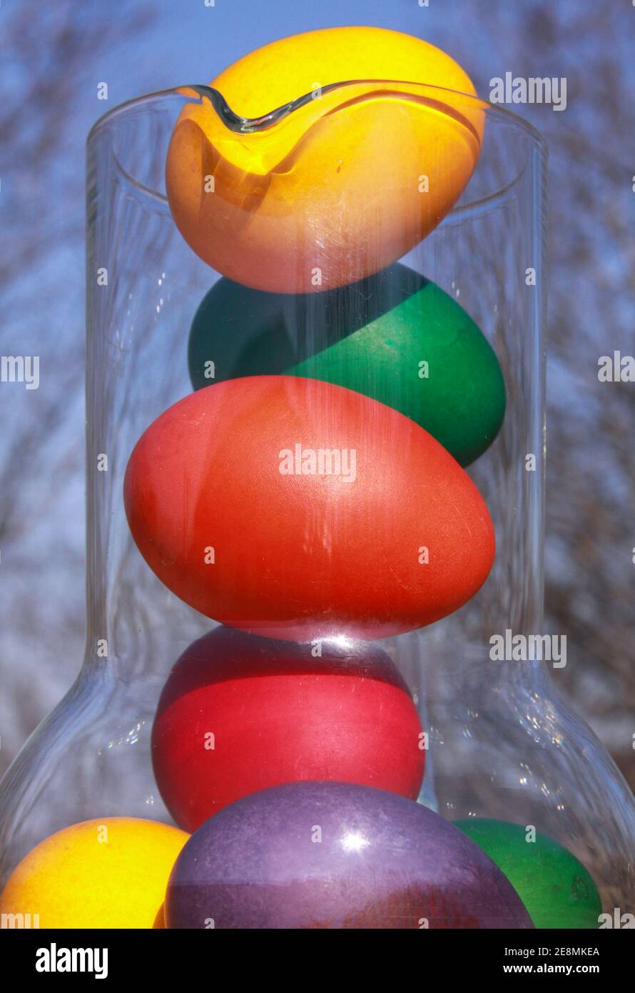 Colored painted Easter eggs in glass vase or carafe in preparation for holiday. Painting chicken or duck eggs is a Christian tradition to celebrate Ea Stock Photo