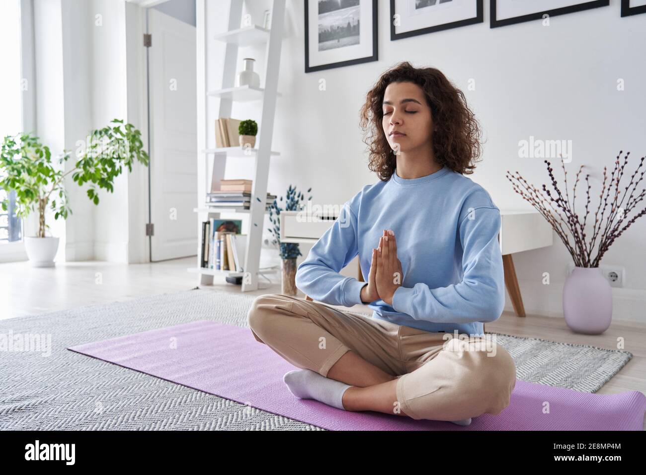 Serene healthy young woman meditating at home doing yoga breathing exercise. Stock Photo