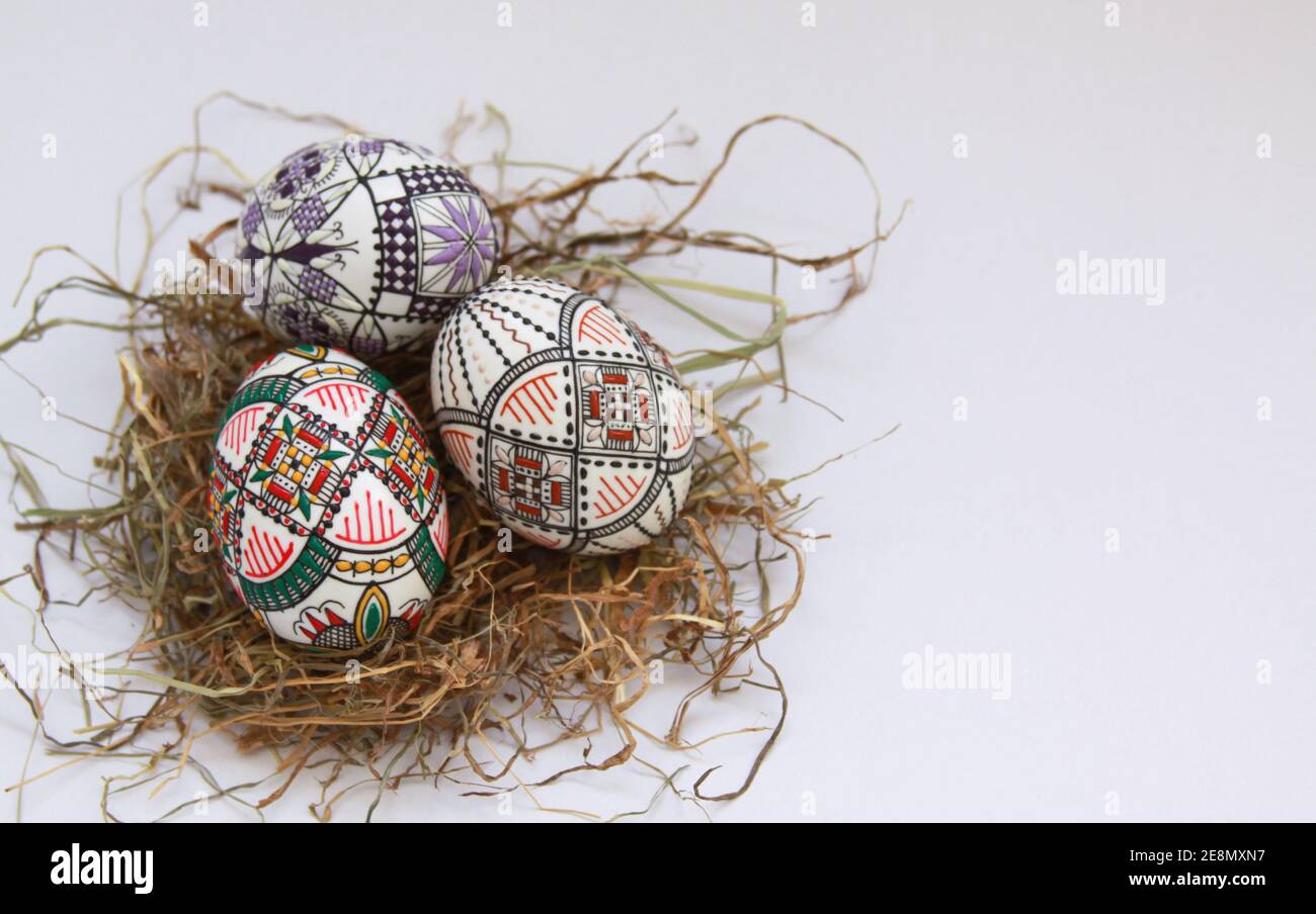 Isolated traditional handmade Easter eggs vintage decoration on hay. Seasonal motif on hand wax painting technique from Bucovina, Romania used to deco Stock Photo