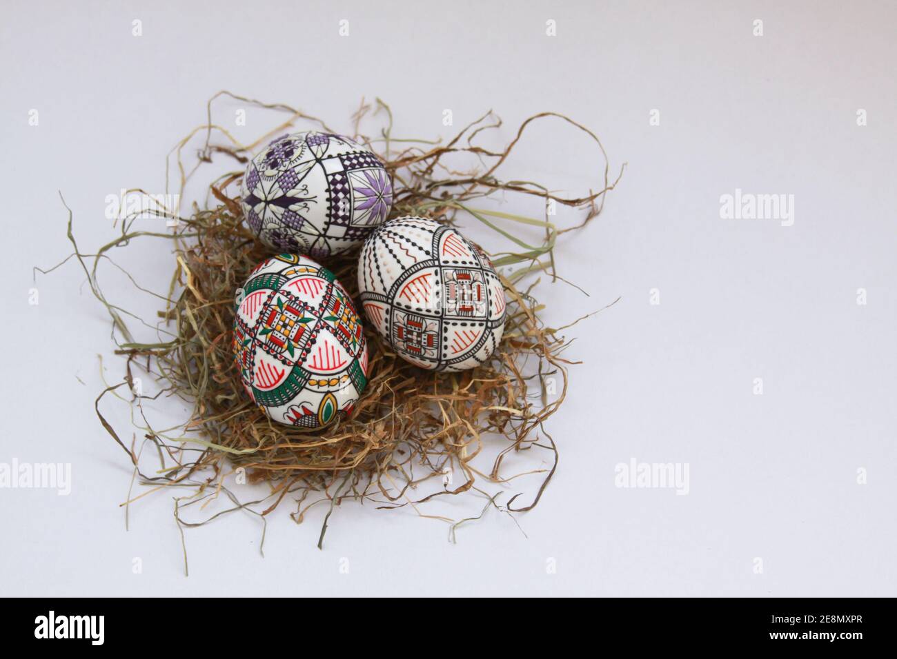 Isolated traditional handmade Easter eggs vintage decoration on hay. Seasonal motif on hand wax painting technique from Bucovina, Romania used to deco Stock Photo